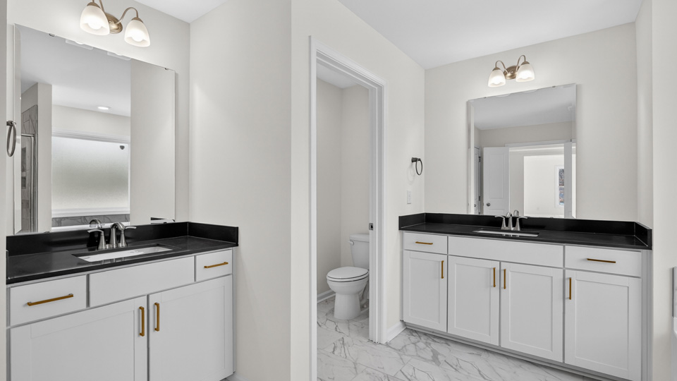 primary bathroom with separate vanities and white cabinets