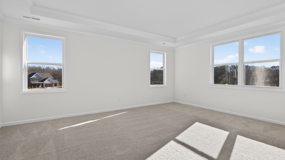Primary bedroom with carpet, windows, and acess to the primary bathroom