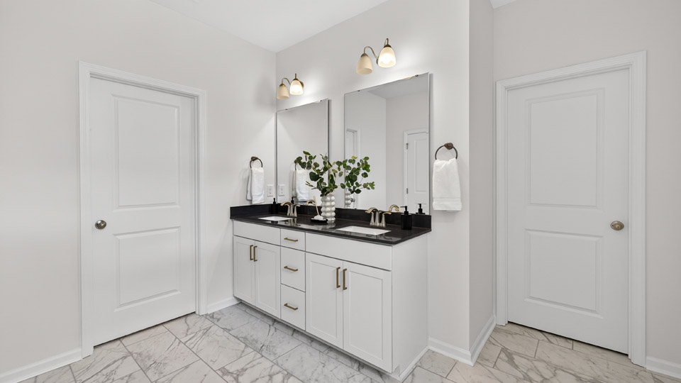 bathroom with dual vanity sinks and white cabinets