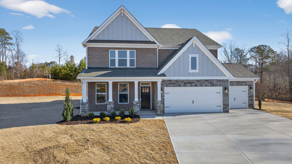 Two story home with blue colored siding with a three car garage
