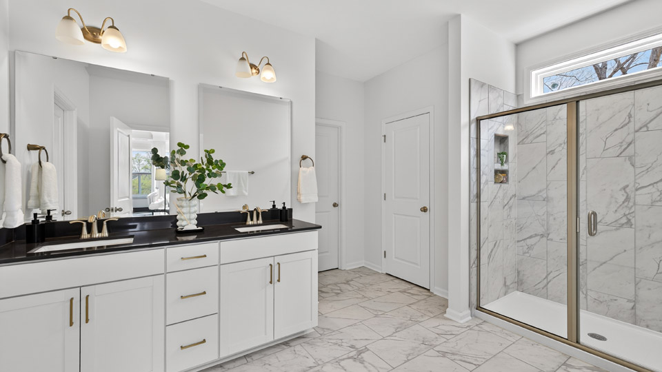 primary bathroom with walk in shower and dual vanity sinks