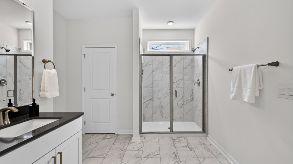 primary bathroom with walk in shower and dual vanity sinks