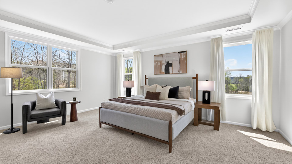 primary bedroom with two windows and carpeting, attached bath