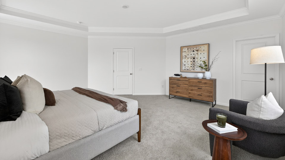 primary bedroom with two windows and carpeting, attached bath