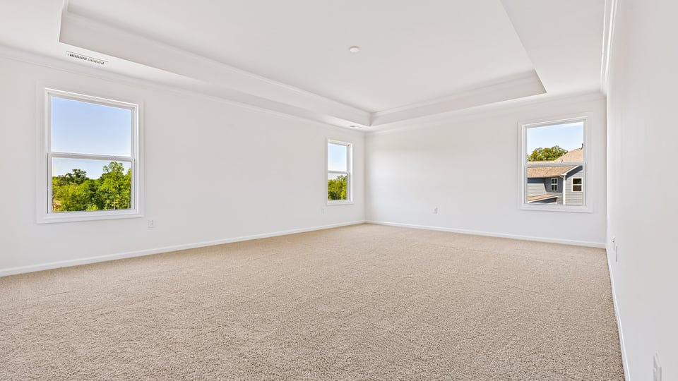 primary bedroom with two windows and carpeting, attached bath