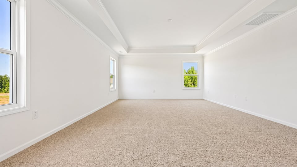 primary bedroom with two windows and carpeting, attached bath