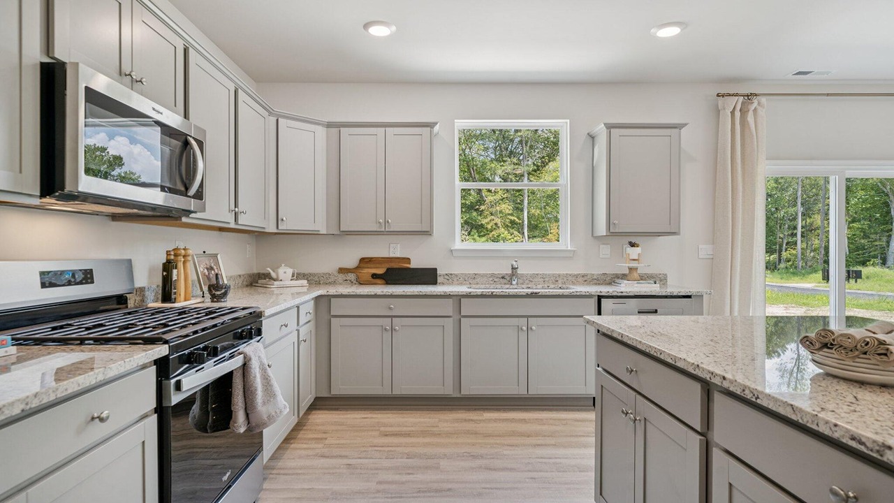 Open-concept kitchen with white cabinets, quartz countertops, and stainless steel appliances.