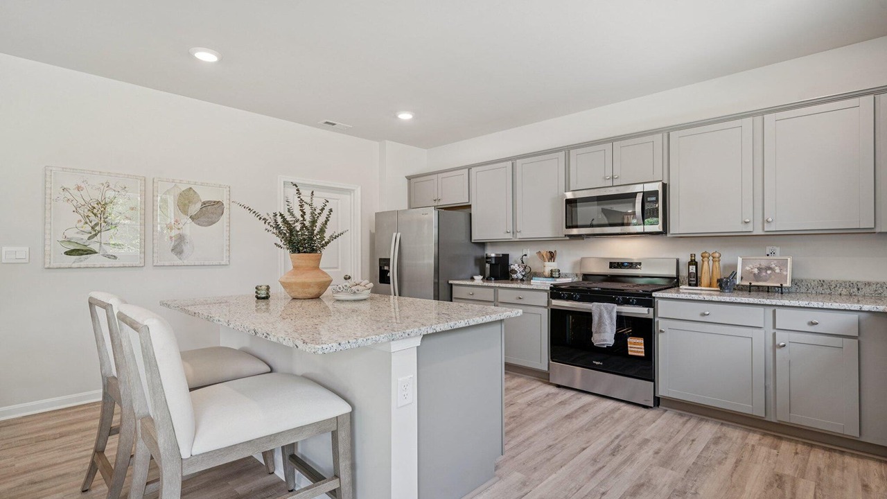 Kitchen with clean white finishes and stainless steel appliances in an open floor plan