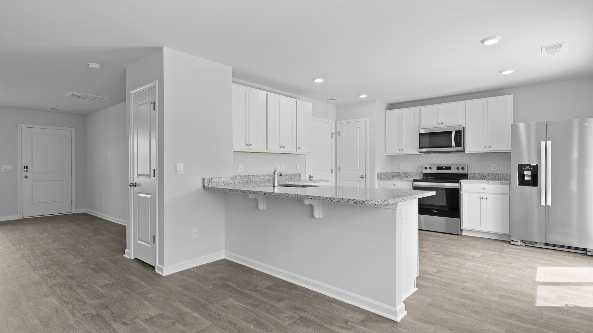 Granite countertops in the kitchen with an island that fits barstools underneath.