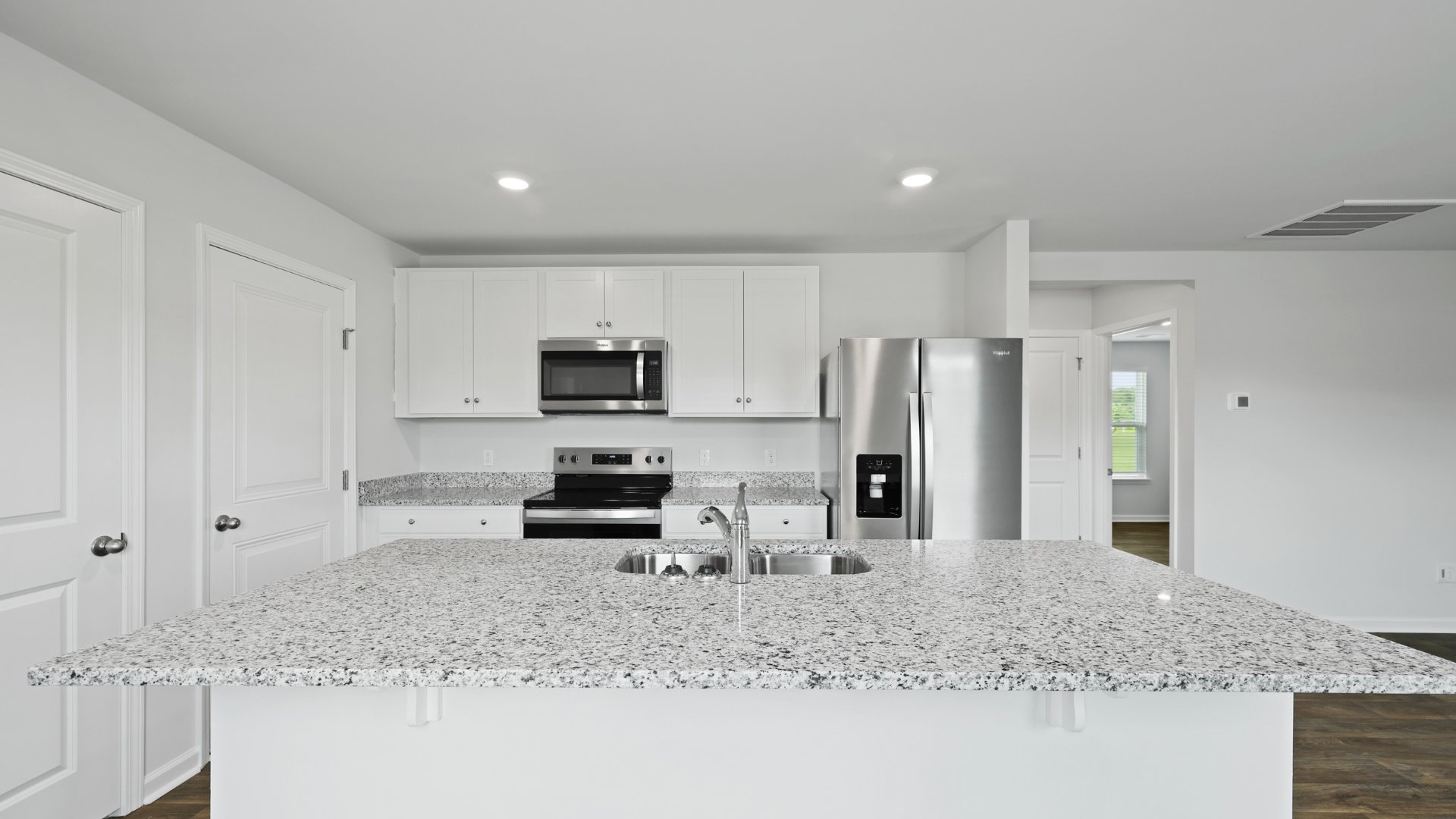 The granite island in the kitchen can fit barstools underneath for extra seating.