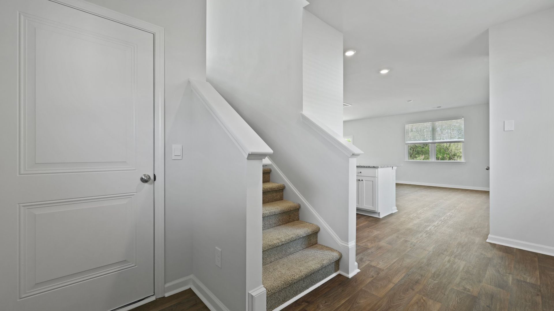 The staircase is located between the entry and kitchen.