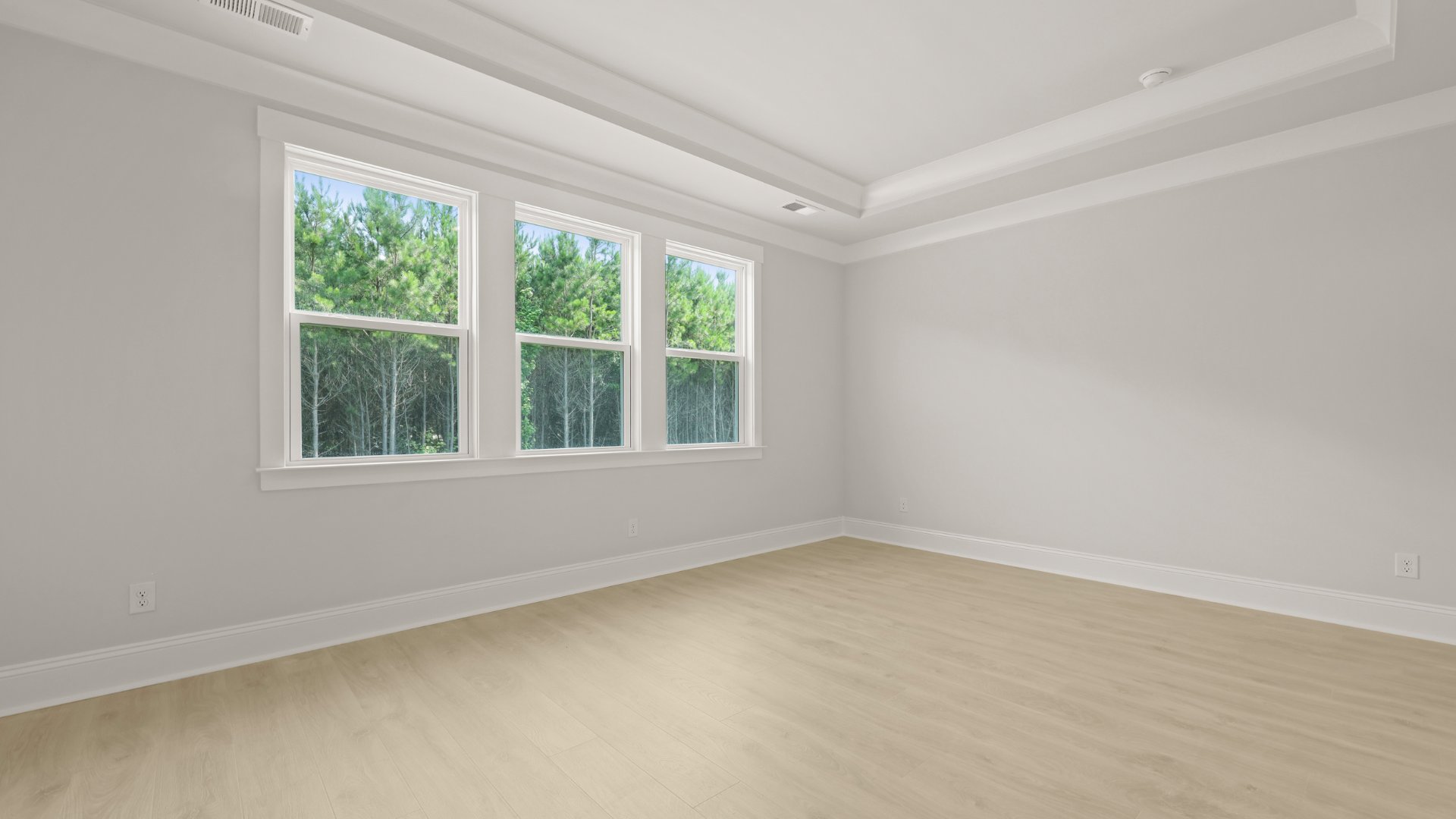 The primary bedroom feature triple windows allowing for natural light to enter.