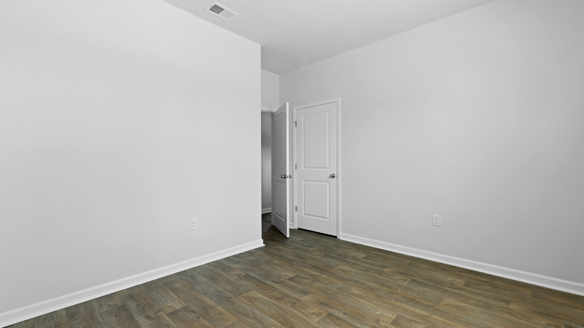 Spacious bedroom 2 with a closet and windows for natural lighting.