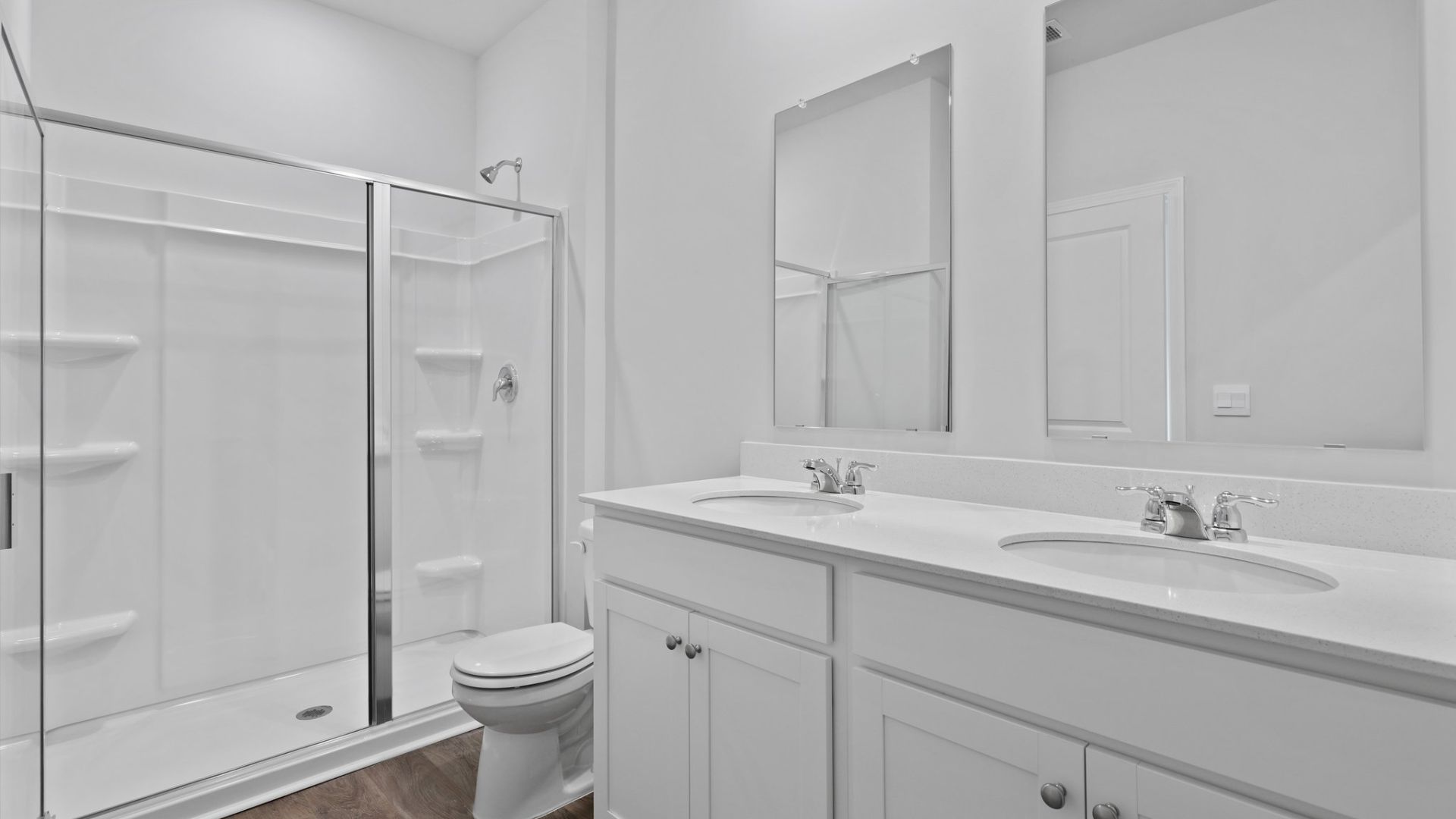 The primary bathroom features double vanities and a glass standup walk-in shower.