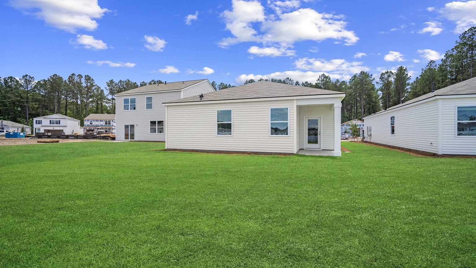 Exterior of the rear of the single-story home with siding, two rear-facing windows, a rear door with a covered porch area