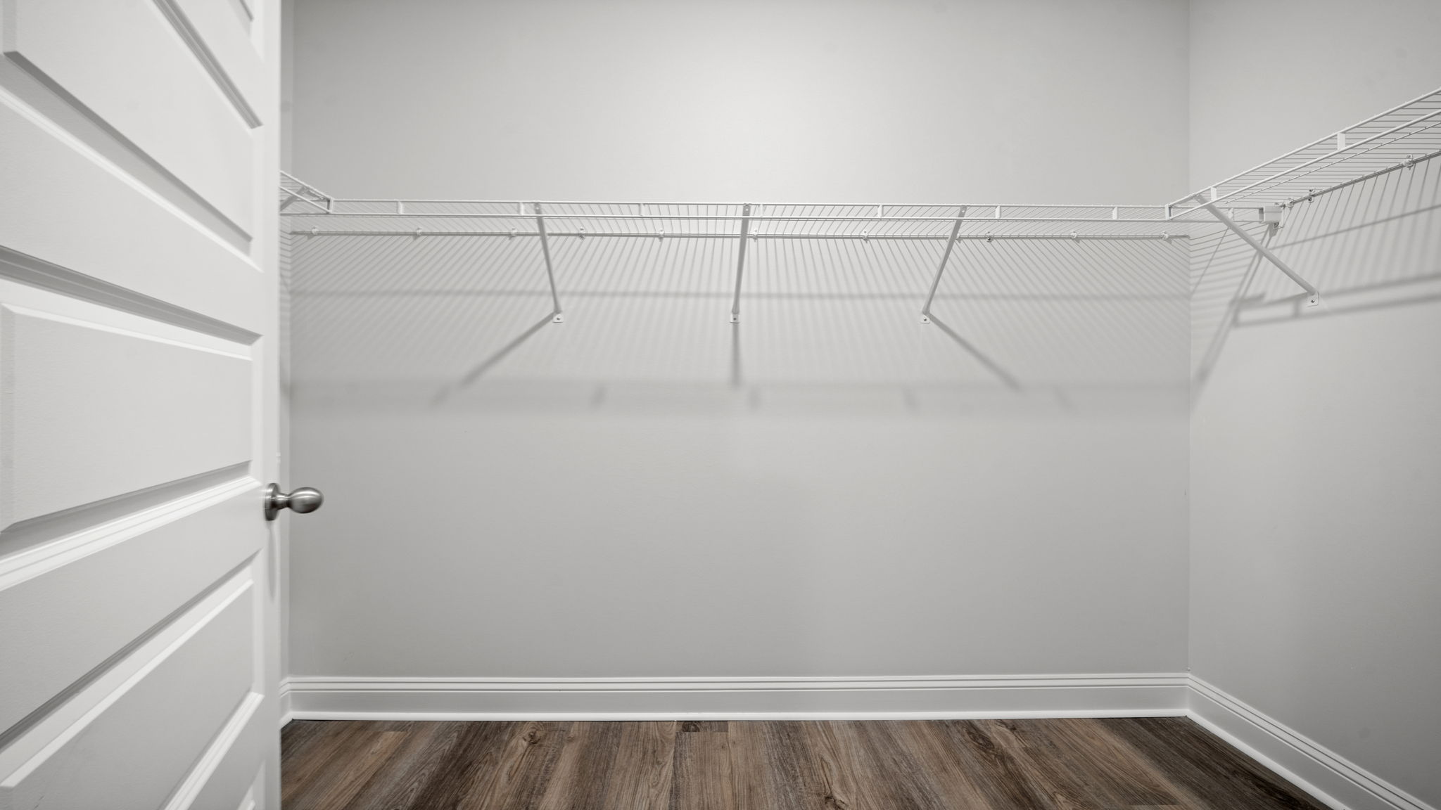 Large walk-in closet with built-in wire shelving, ample hanging space, and wood-look flooring.