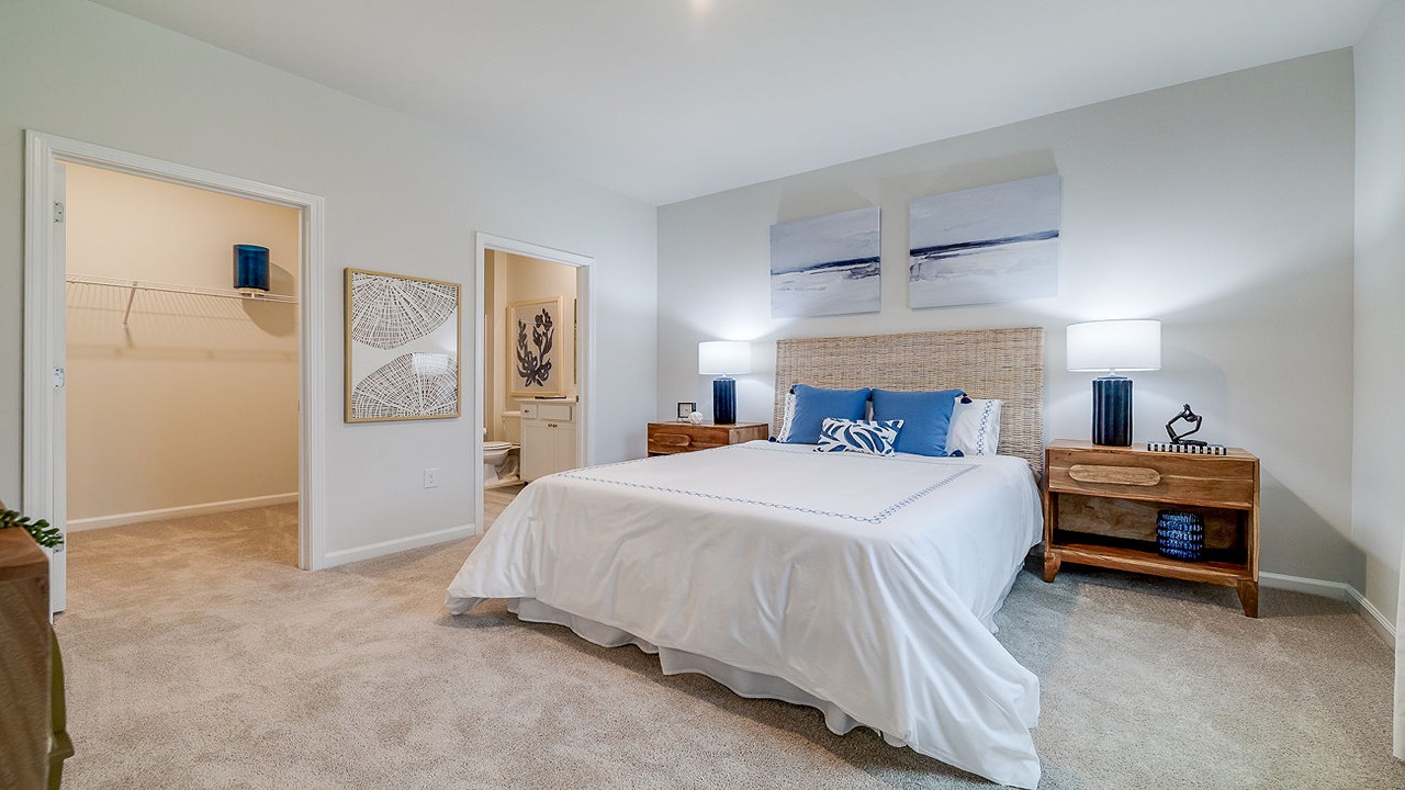 Primary bedroom decorated with a bed, dresser and a side table