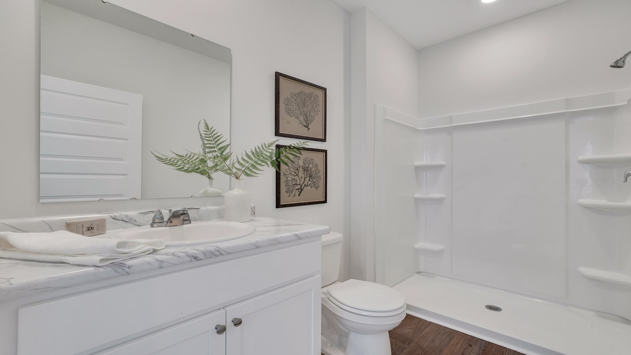 Spa-inspired primary bathroom in the Helena home featuring dual vanities and a walk-in shower