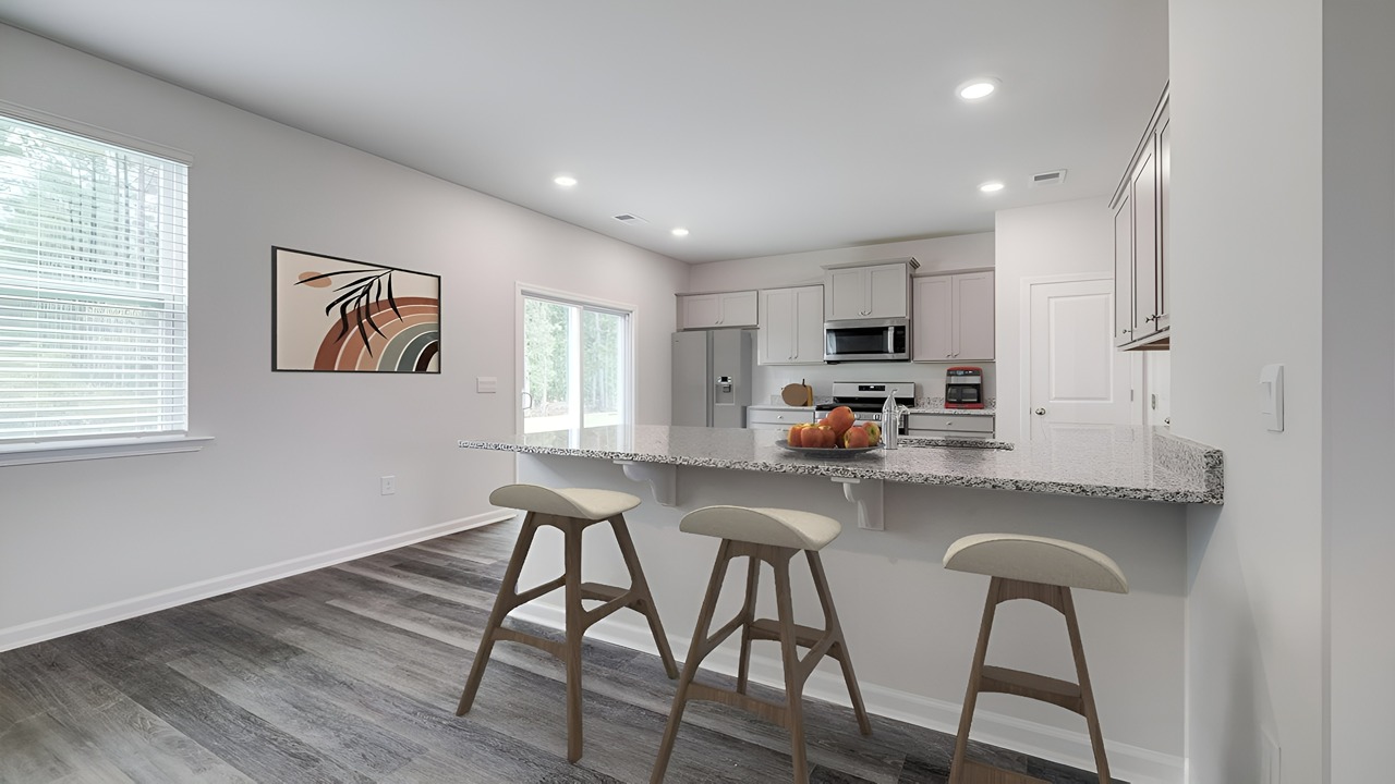 Open-concept kitchen in the Brandon floor plan featuring a large island, quartz countertops, stainless steel appliances, shaker-style cabinets, and ample storage.