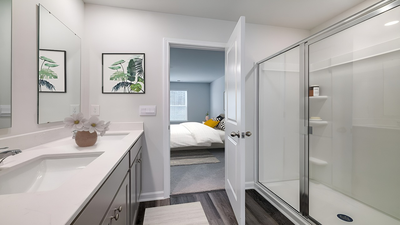 Elegant primary bathroom in the Brandon floor plan featuring dual vanities, walk-in shower, modern fixtures, and a spacious walk-in closet.