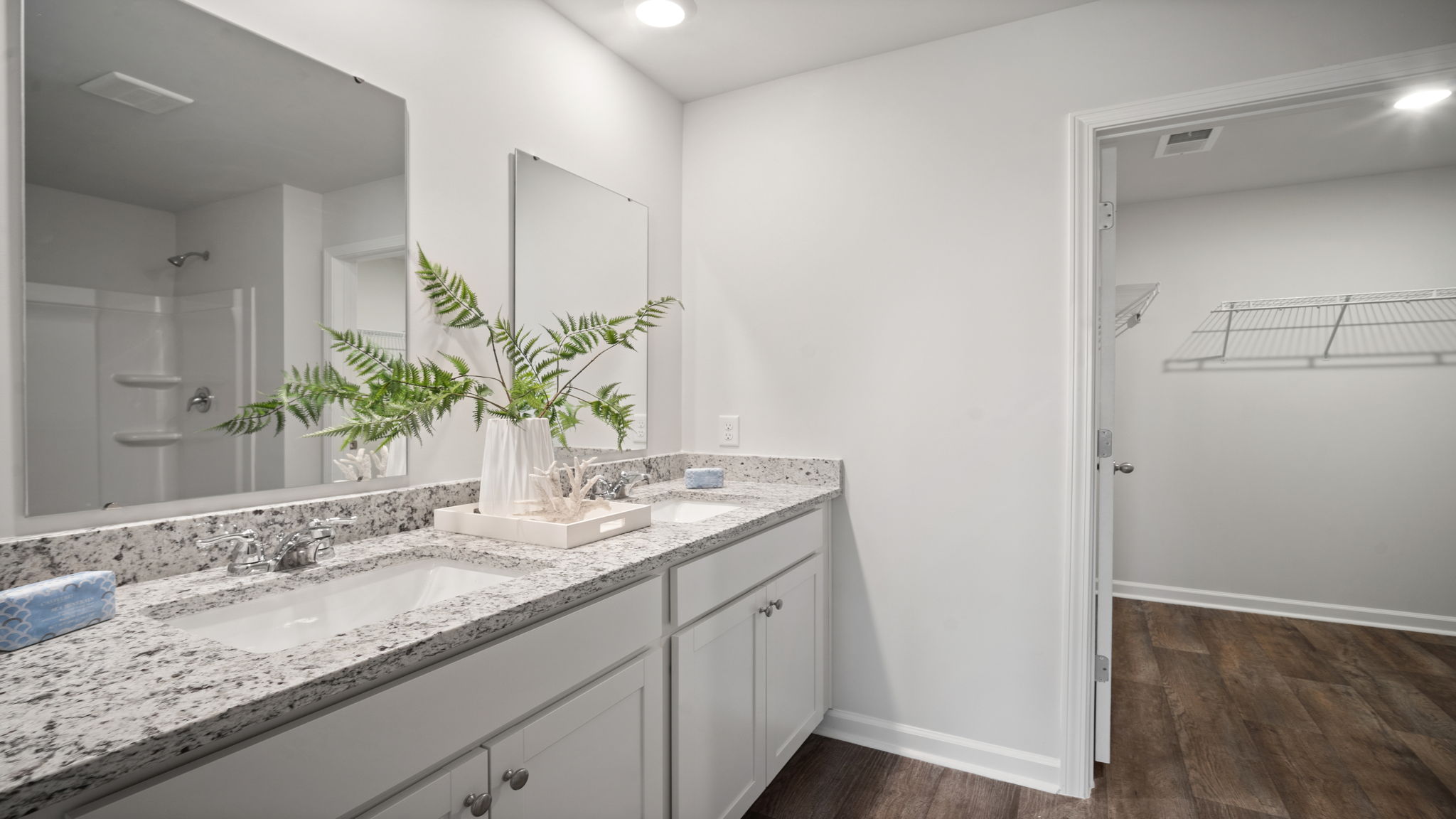 Primary bathroom with tile walk in shower, bright light fixtures, and with built in shelves. connecting walk-in closet.