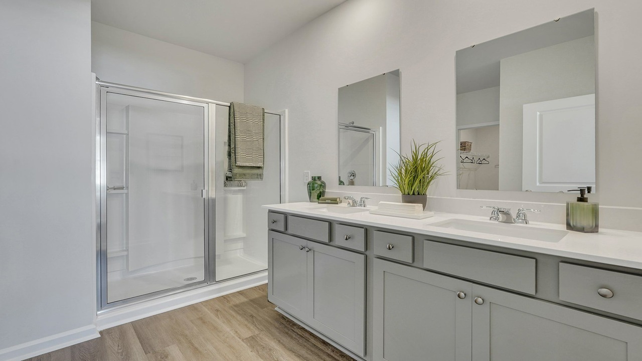 Primary bathroom with double vanities and a stand-up shower