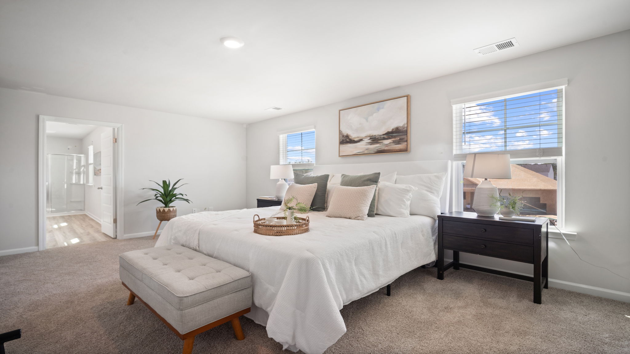 Primary bedroom with carpeted floors, large windows, and trey ceilings.