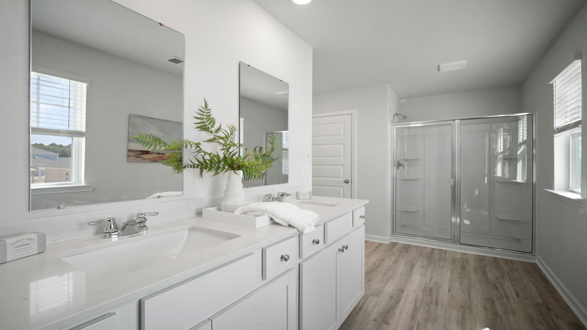 Primary bathroom with tile walk in shower, bright light fixtures, and with built in shelves. connecting walk-in closet.