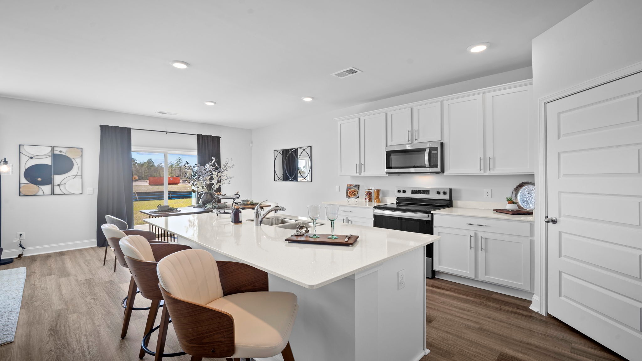 Modern kitchen in the Hayden floor plan featuring quartz countertops, stainless steel appliances, shaker-style cabinetry, a large center island, and walk-in pantry.