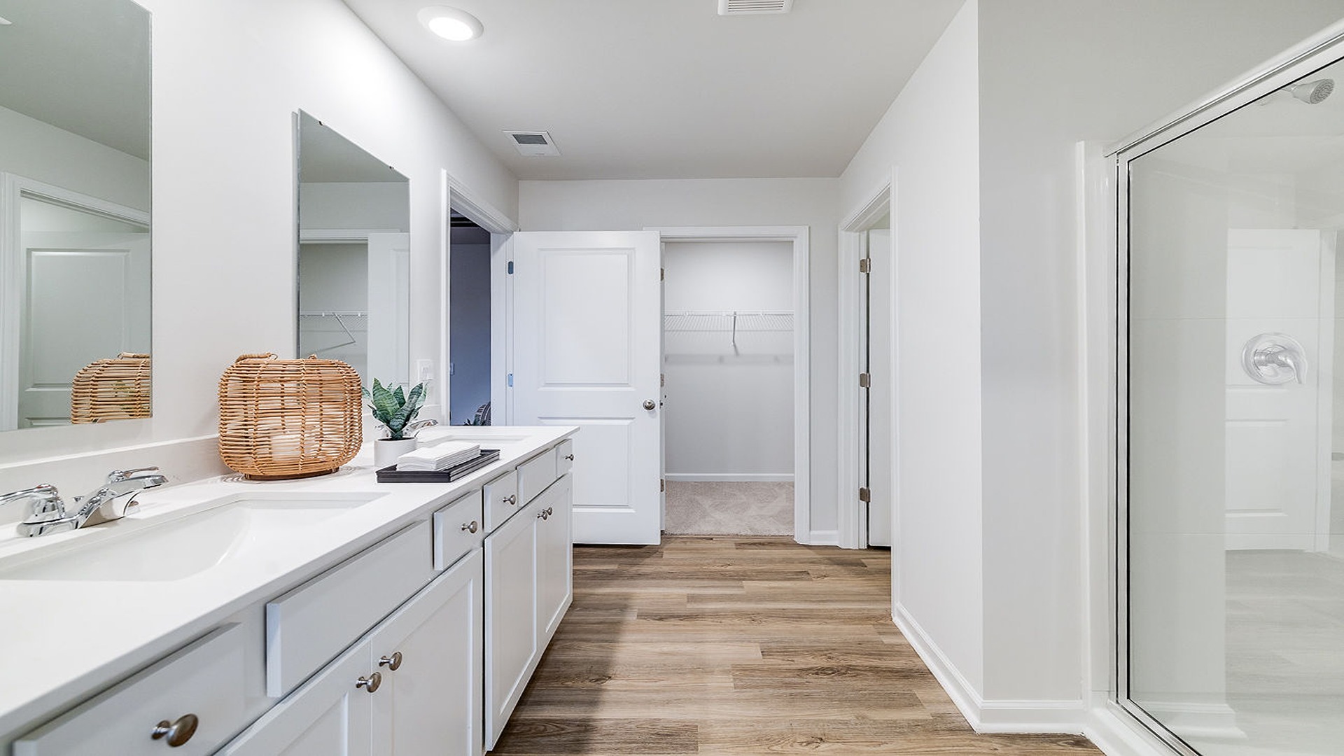 Primary bathroom with double vanities and a stand-up shower