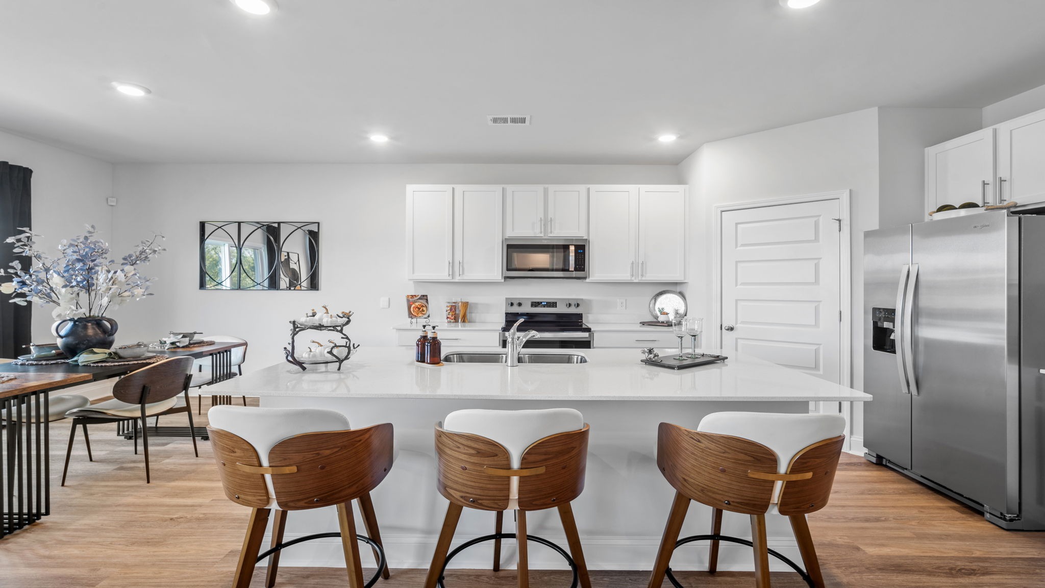 Bright kitchen with modern cabinetry, oversized island seating, and seamless flow into the dining and family room areas.