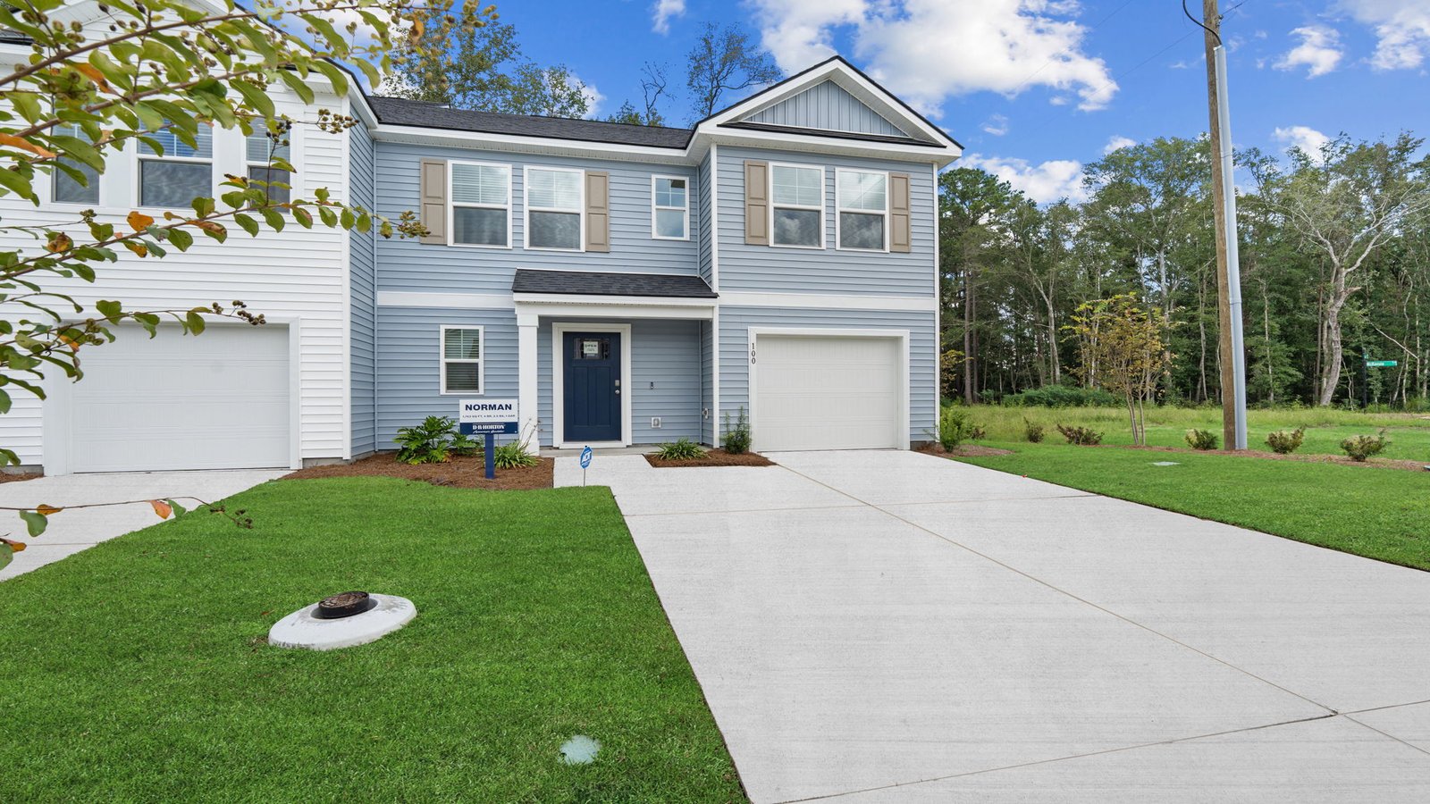 Front exterior of the Norman townhome floor plan featuring attached garage, covered entry, and professionally landscaped yard