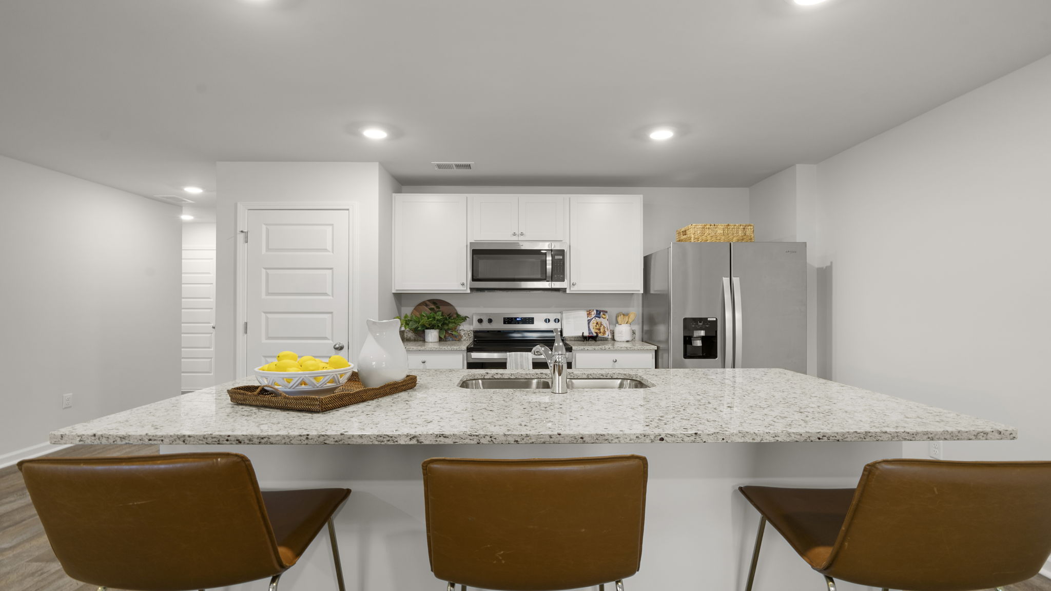 Designer kitchen with granite countertops, large center island, white cabinets, stainless steel appliances, and bar seating.