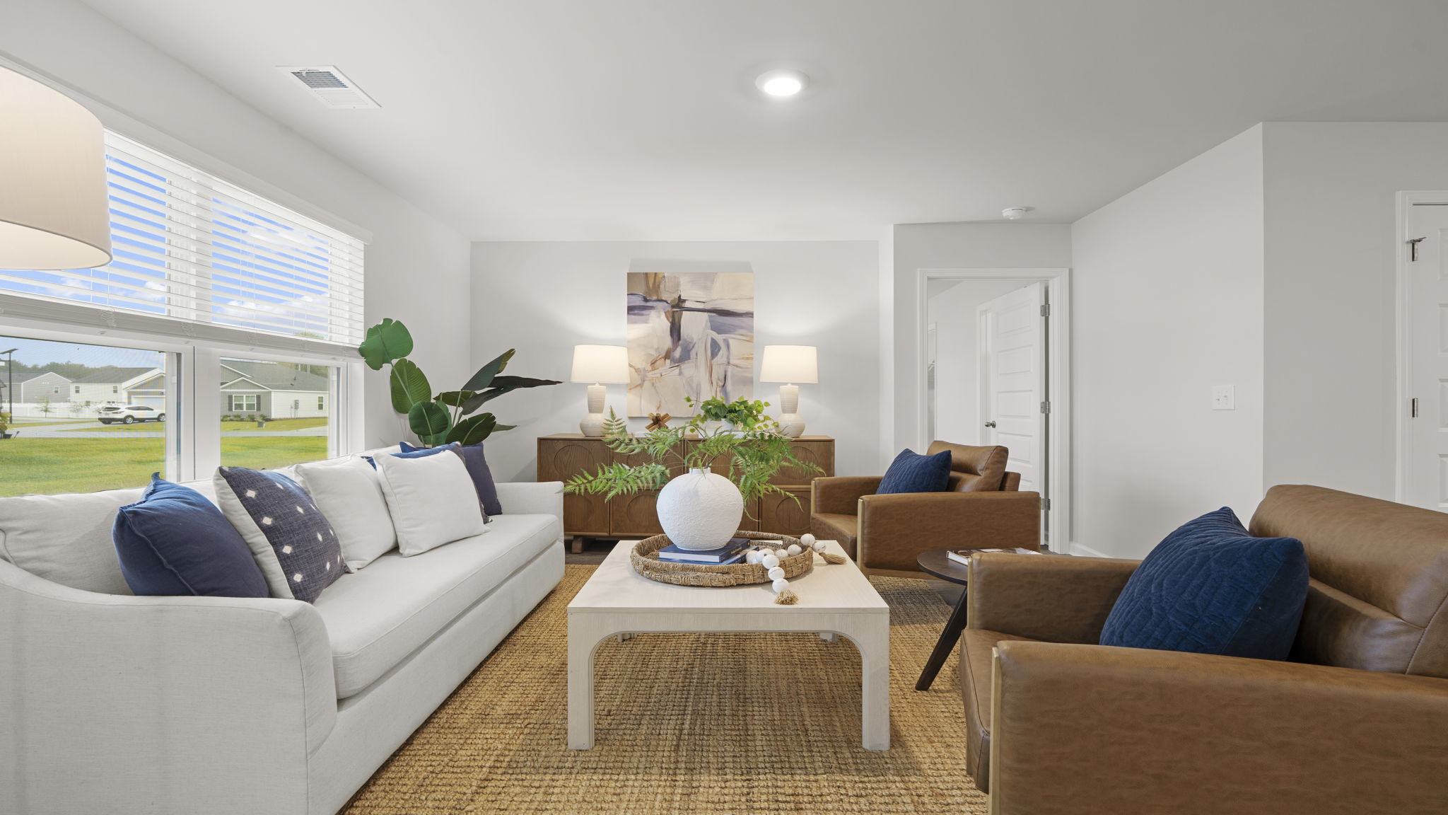 Bright great room with open floor plan, large windows, and direct access to kitchen and dining spaces.