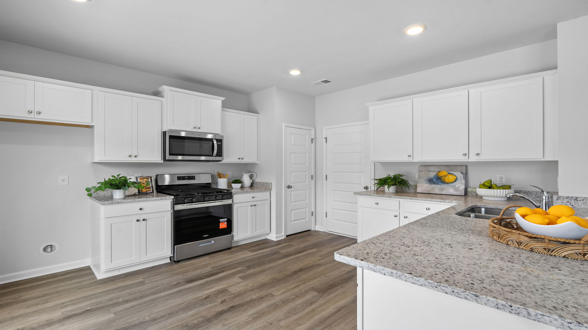Bright kitchen with white cabinets, stainless steel appliances, and island