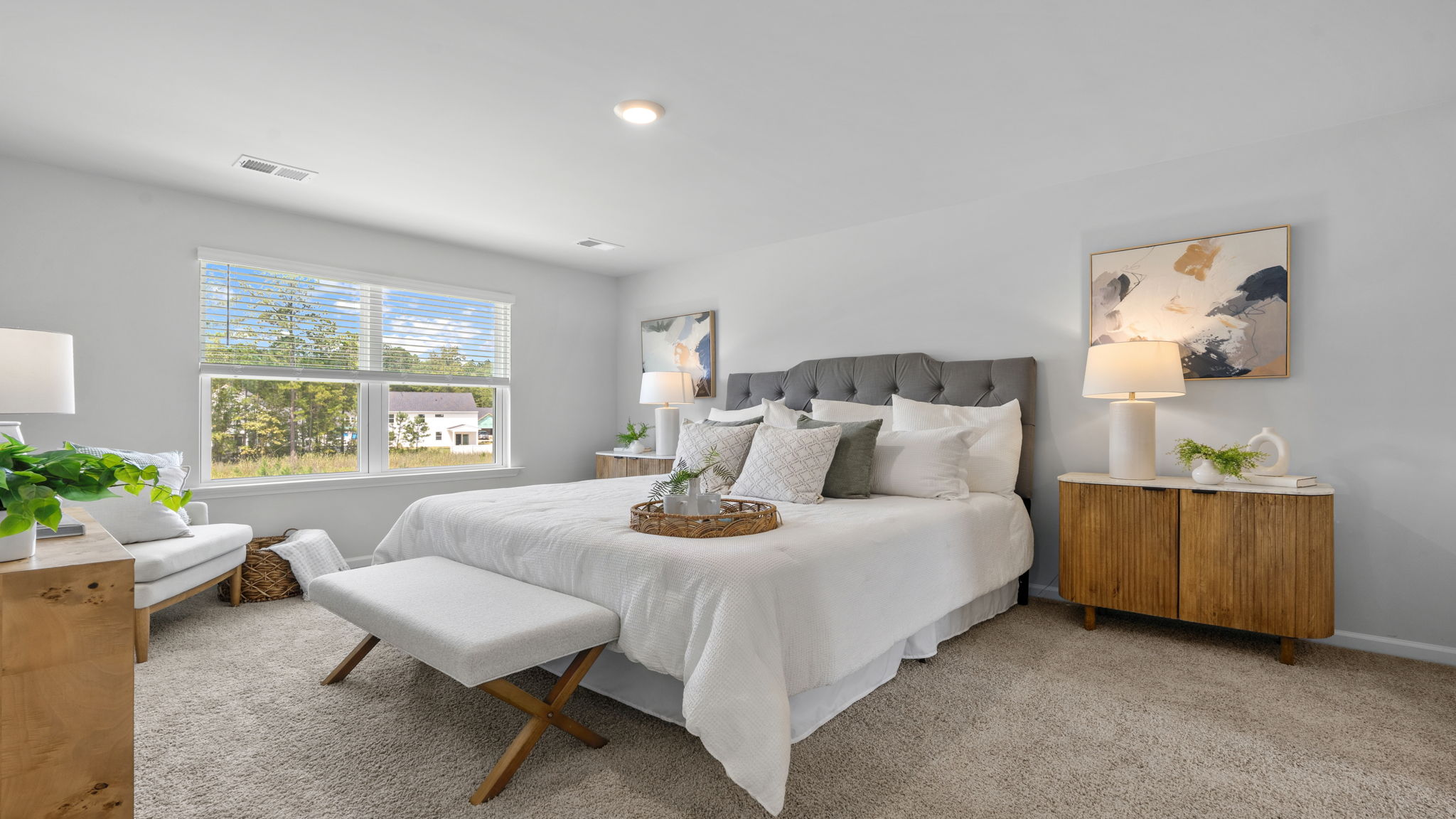 Bright primary bedroom with multiple windows and dresser