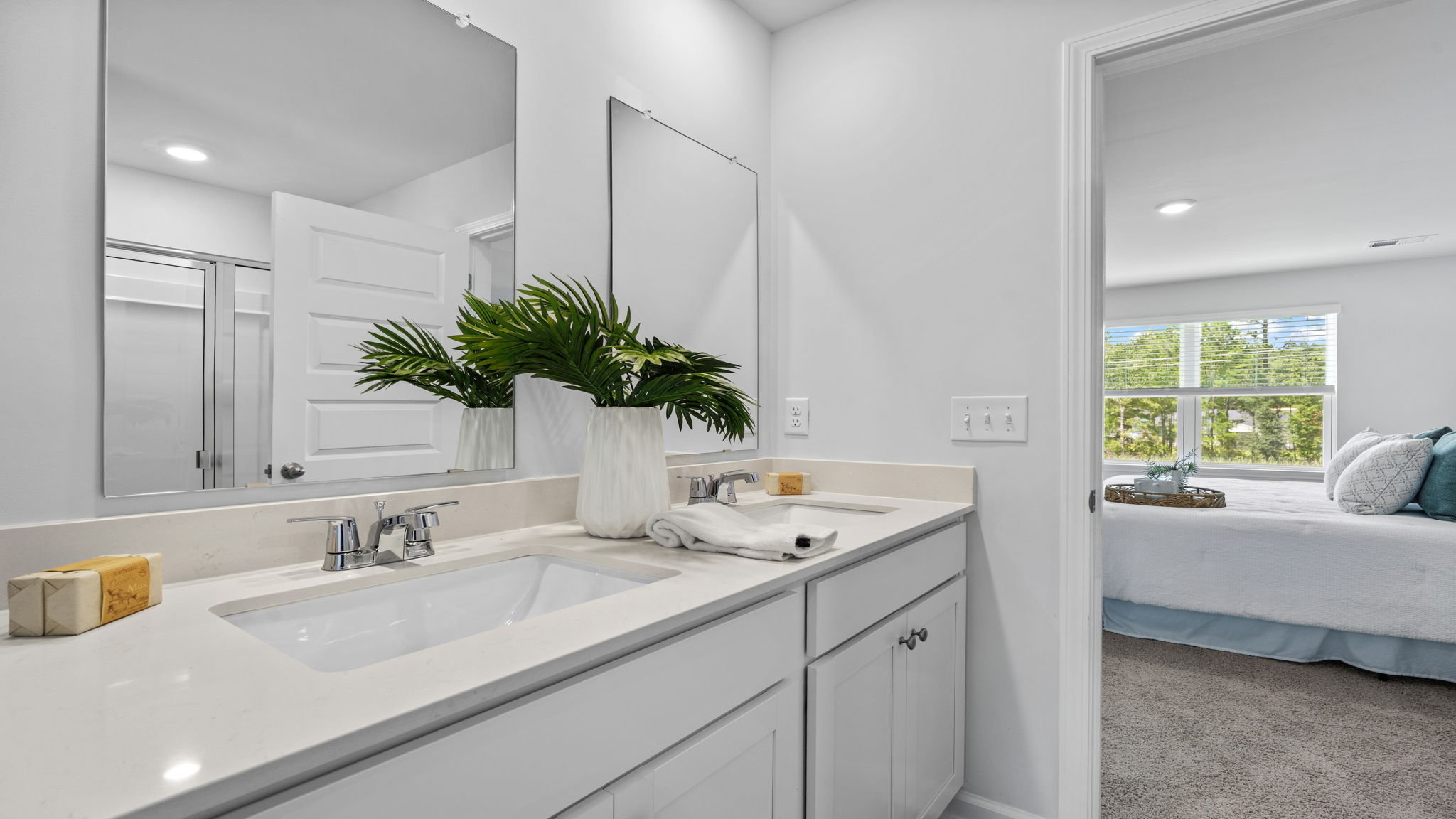 Double vanity bathroom with white cabinetry and large mirror
