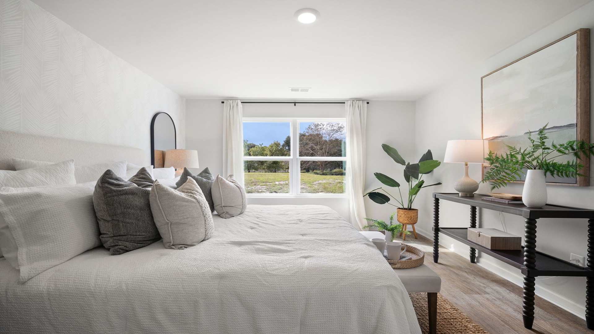 Primary bedroom with hardwood floors, large windows, and trey ceilings.