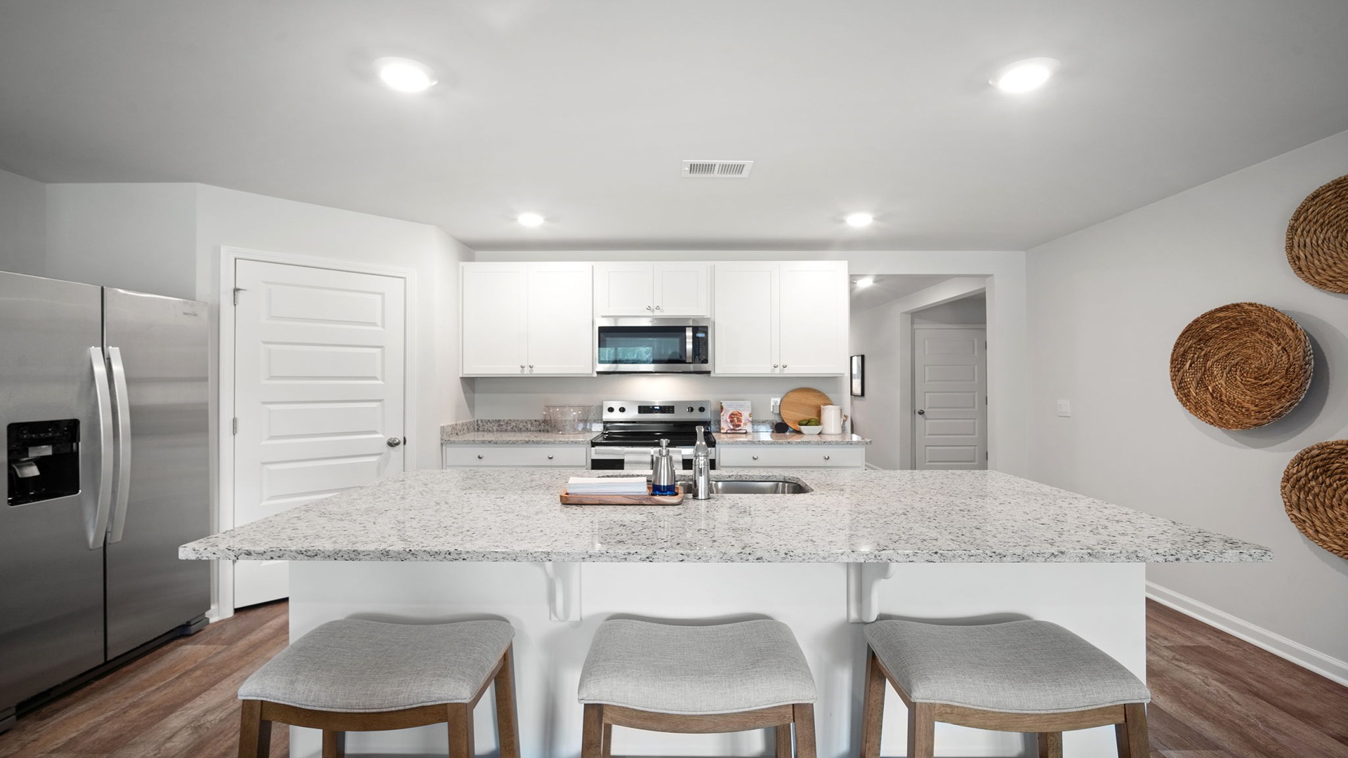 Kitchen area with granite countertops, large island, cabinets, tile backsplash, and stainless steel appliances
