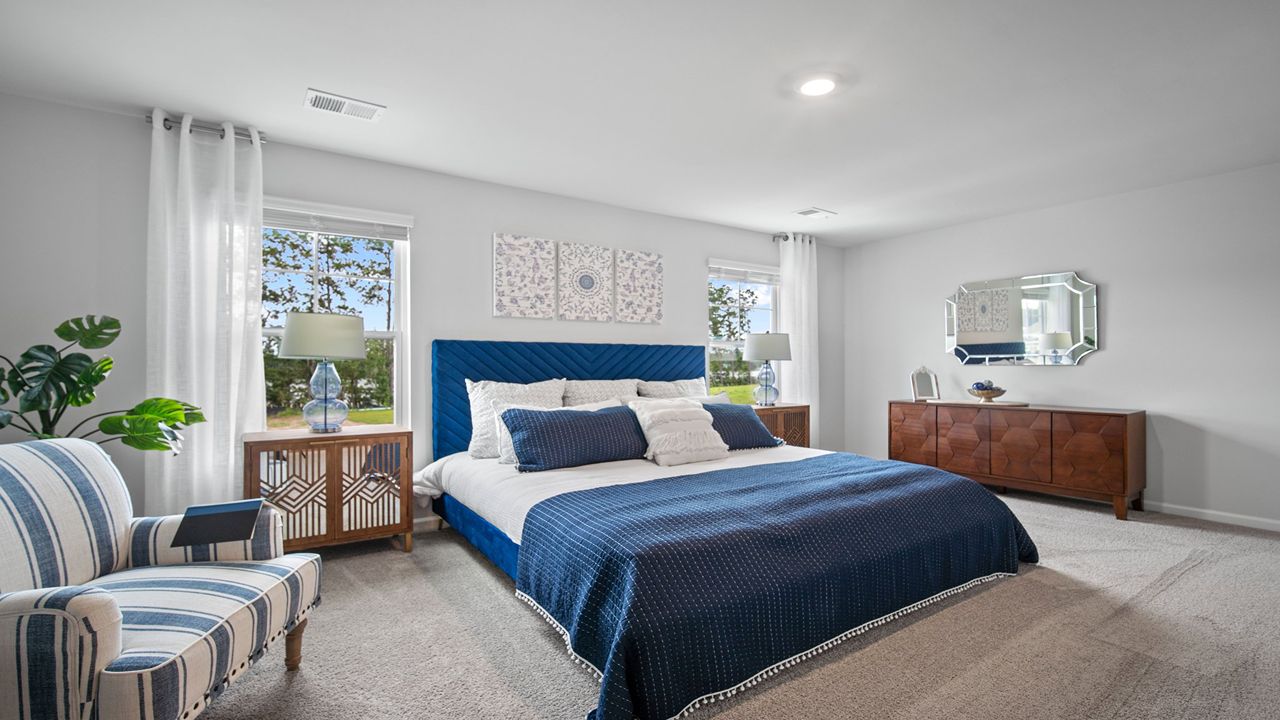 Primary bedroom decorated with a bed, side table and a mirror and a chair