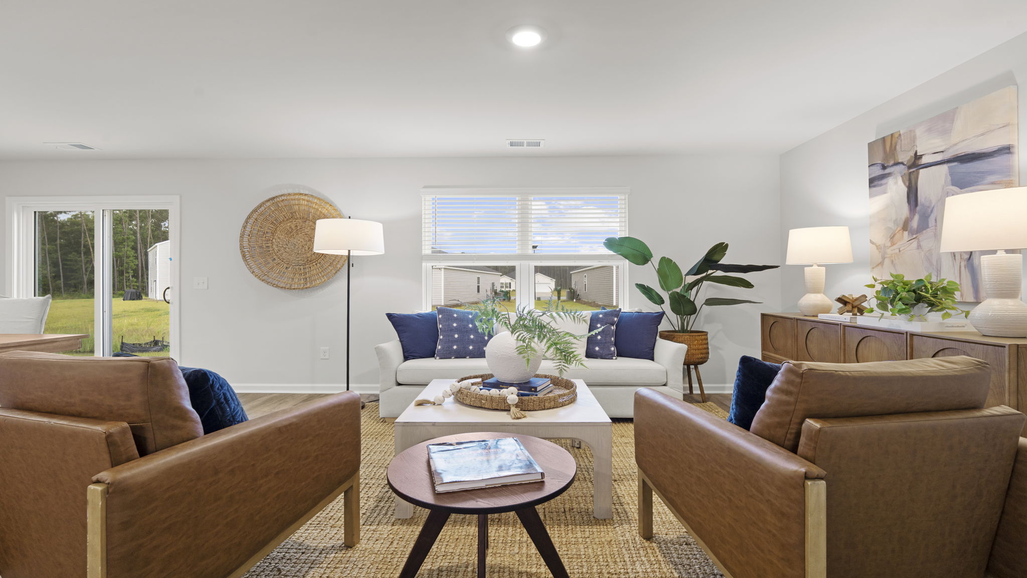 Freeport new construction home featuring a bright open-concept family room with luxury vinyl plank flooring, large windows, comfortable gathering space, and easy access to the patio and backyard.