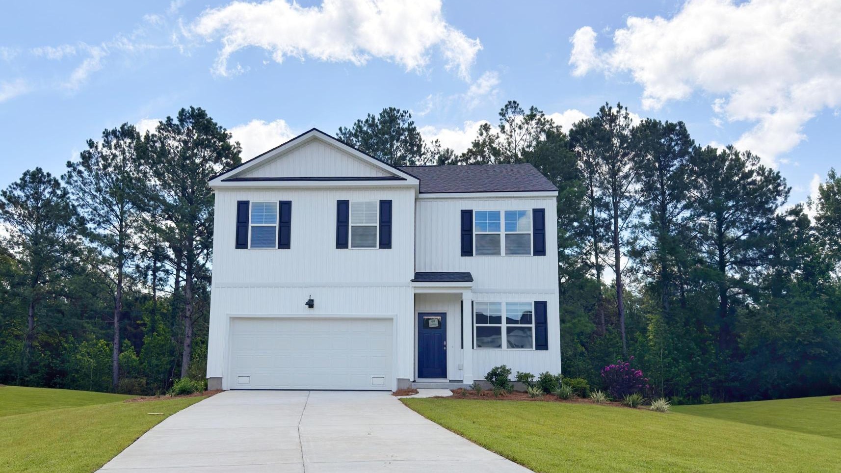 Front of home with long driveway and large yard