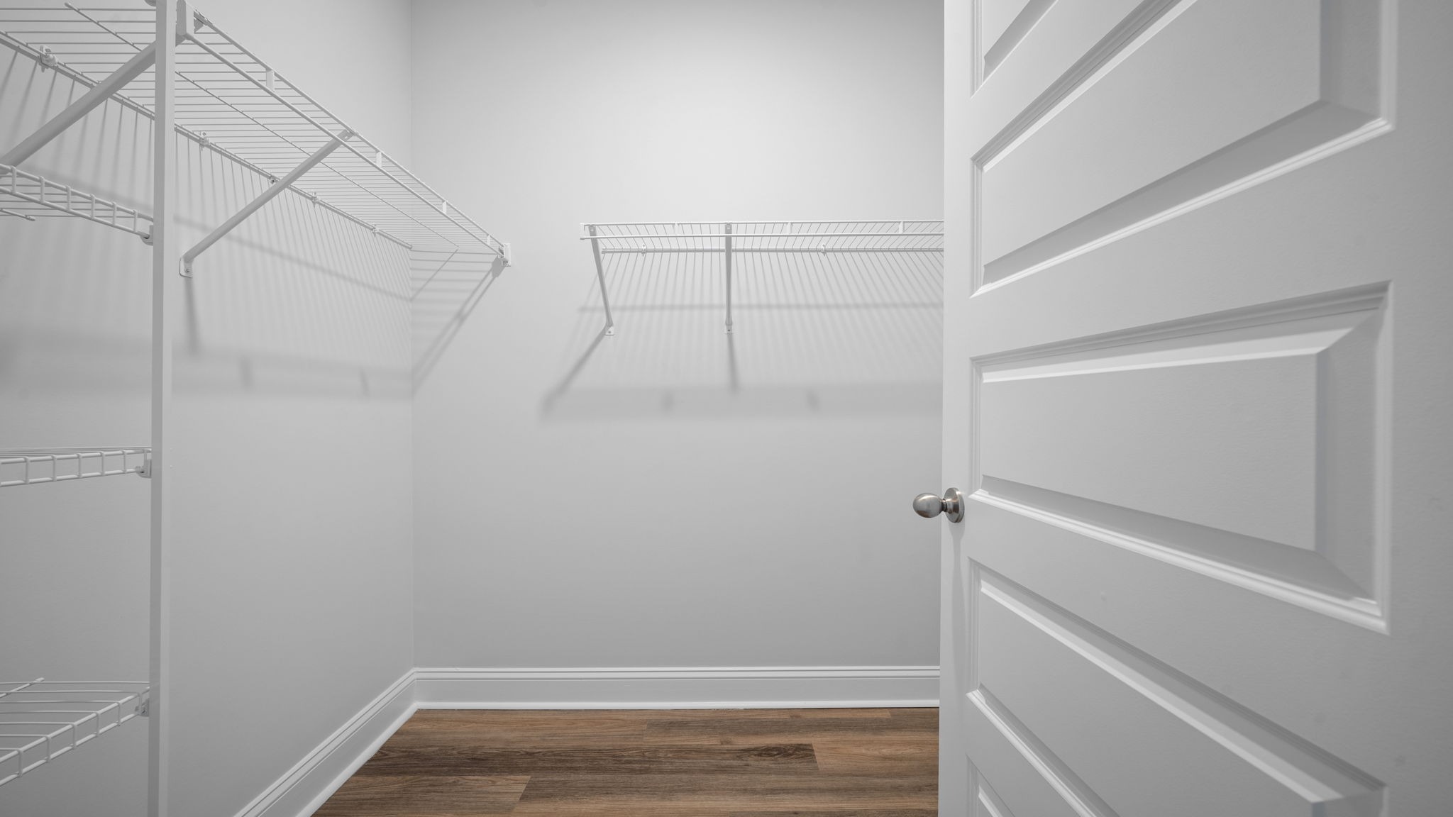 Closet with brown flooring.