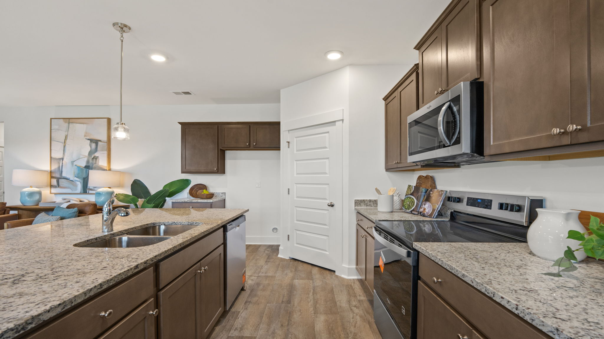 Kitchen with brown cabinets, stainless steel appliances, pendant lighting, and spacious countertops.