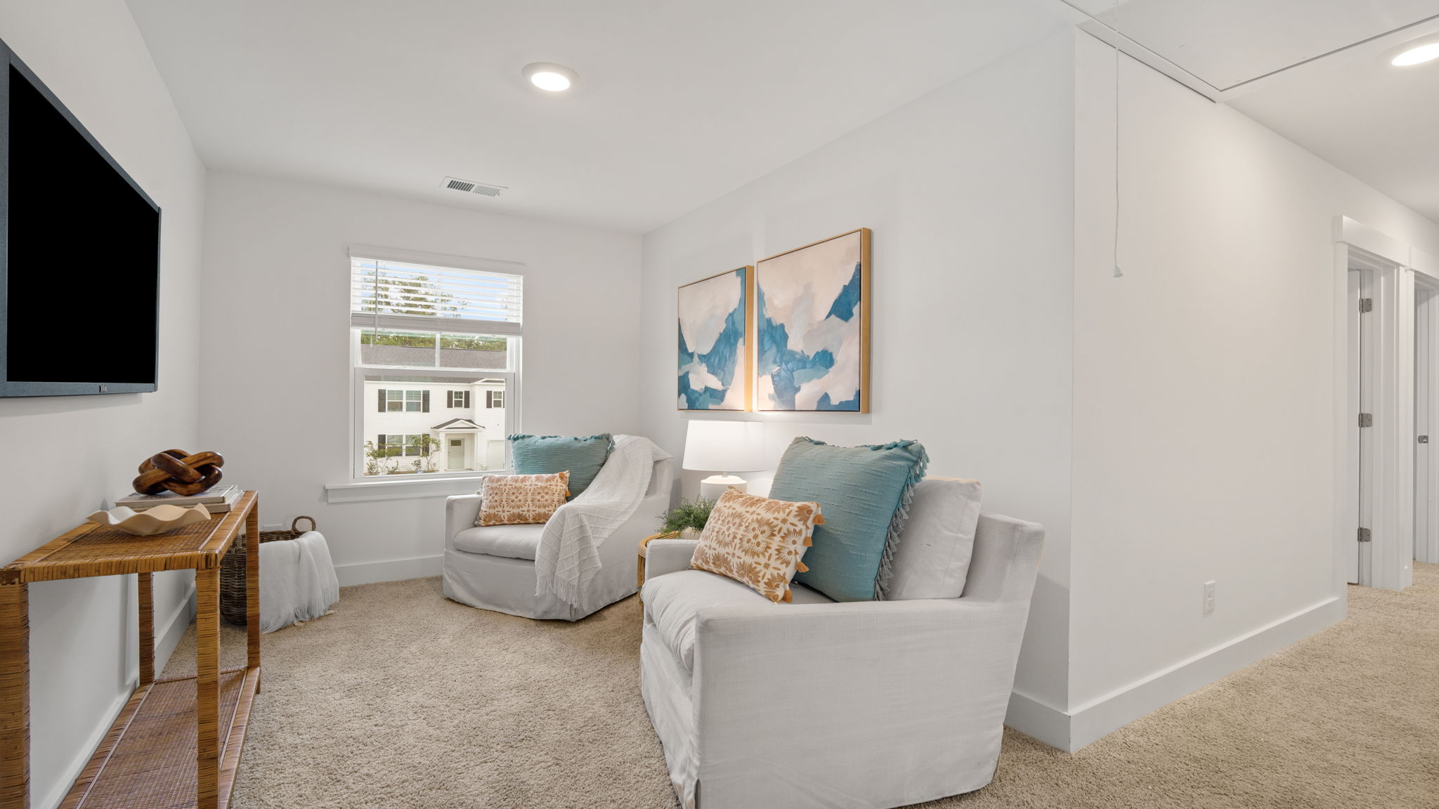 Upstairs loft area with seating, natural light, and neutral finishes.