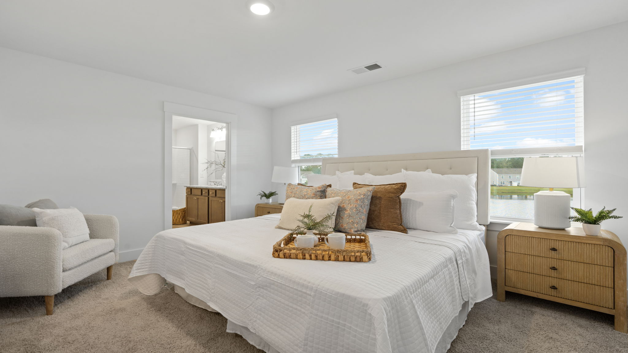 Spacious bedroom with large windows, neutral carpet, and natural light.