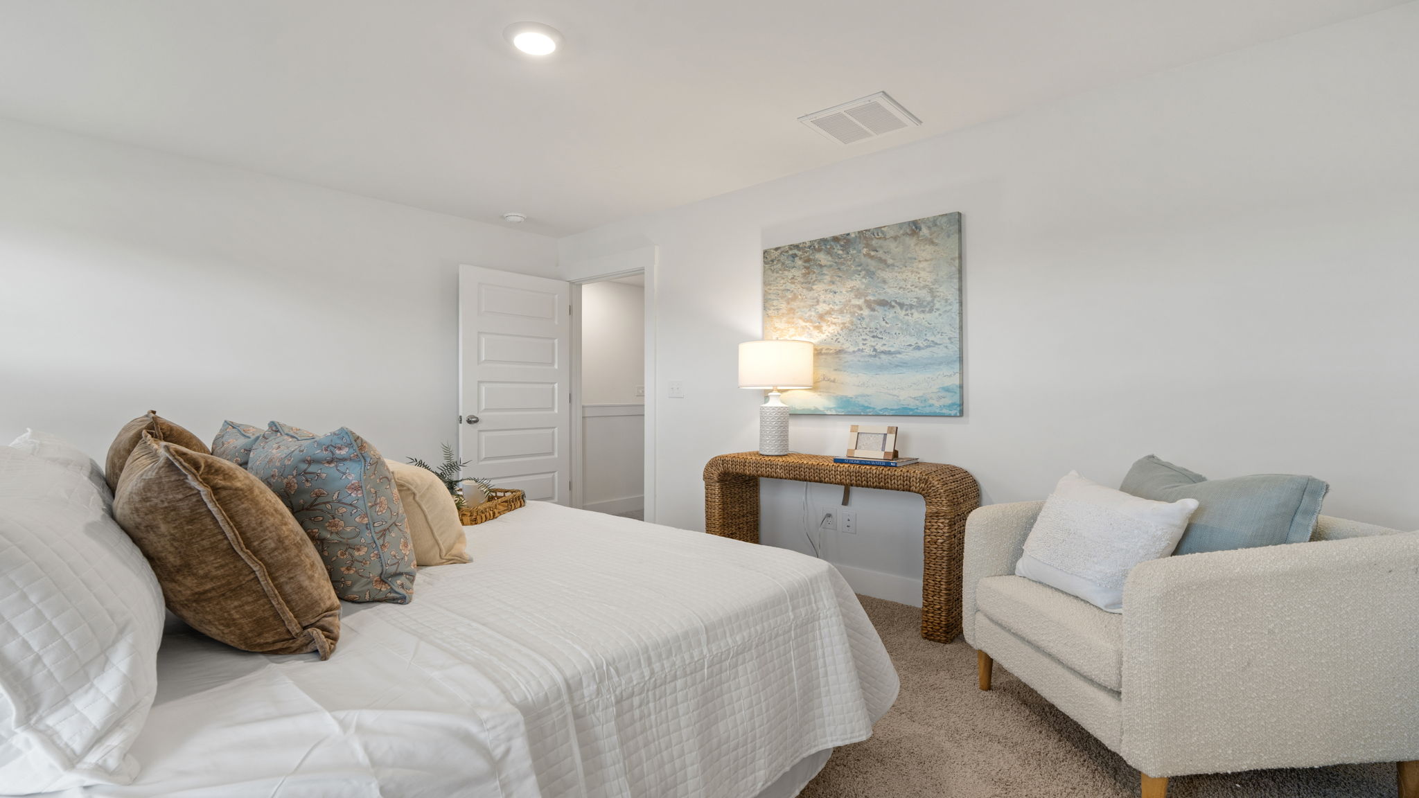Bedroom featuring neutral carpeting, natural light, and sitting area.