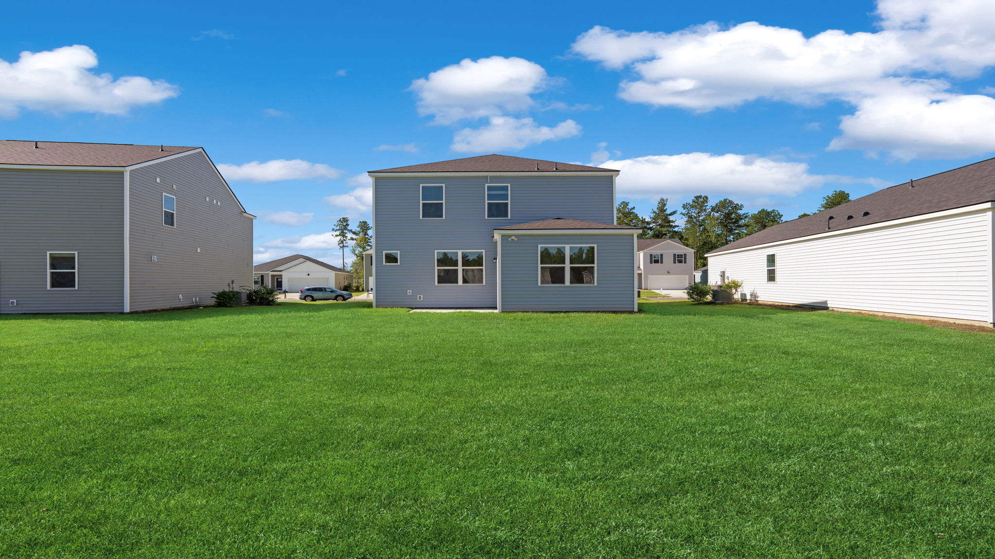 Backyard view showing the rear exterior of the two-story home and open lawn.