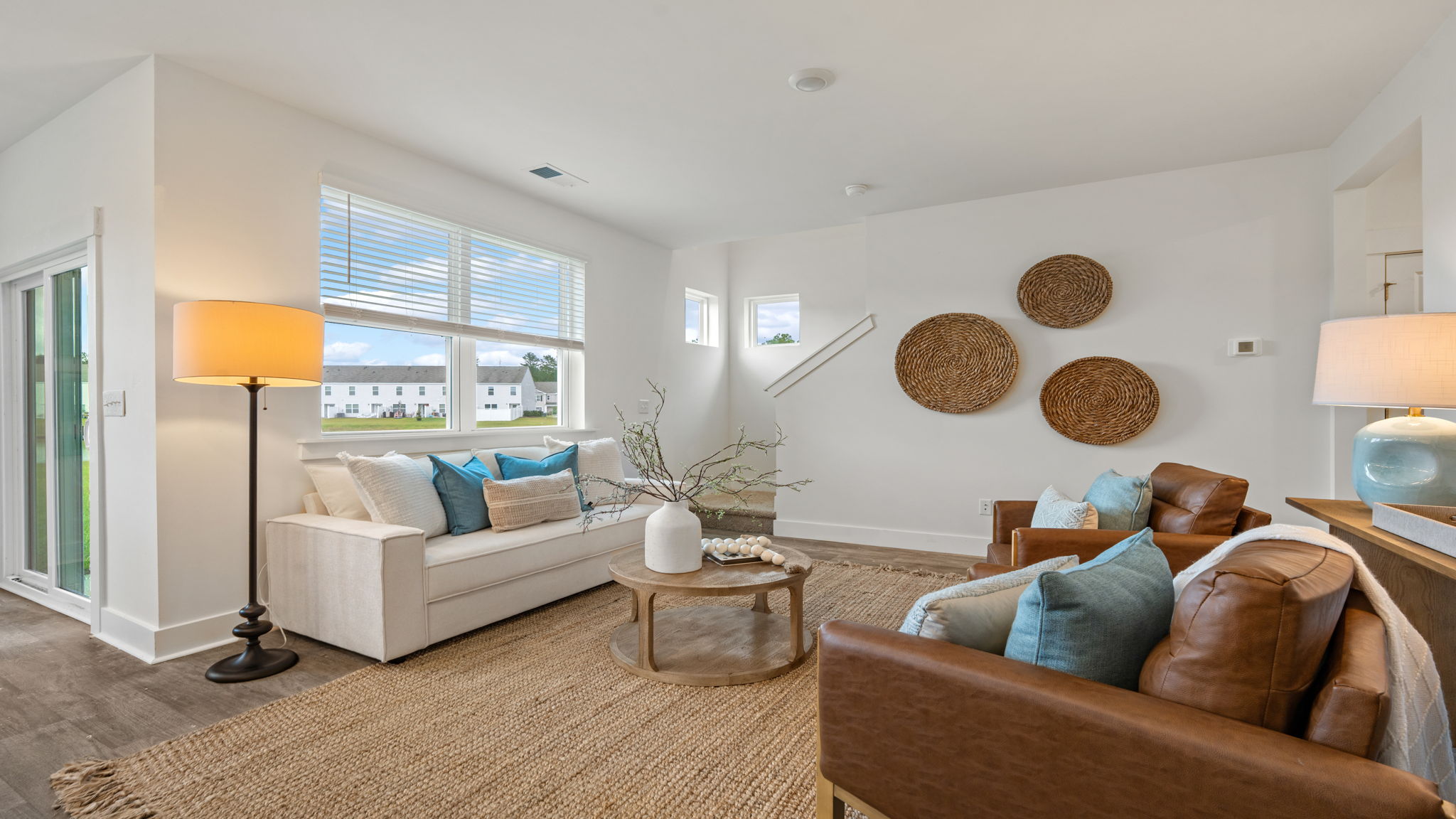 Living room with natural light, neutral finishes, and an open view toward the kitchen.