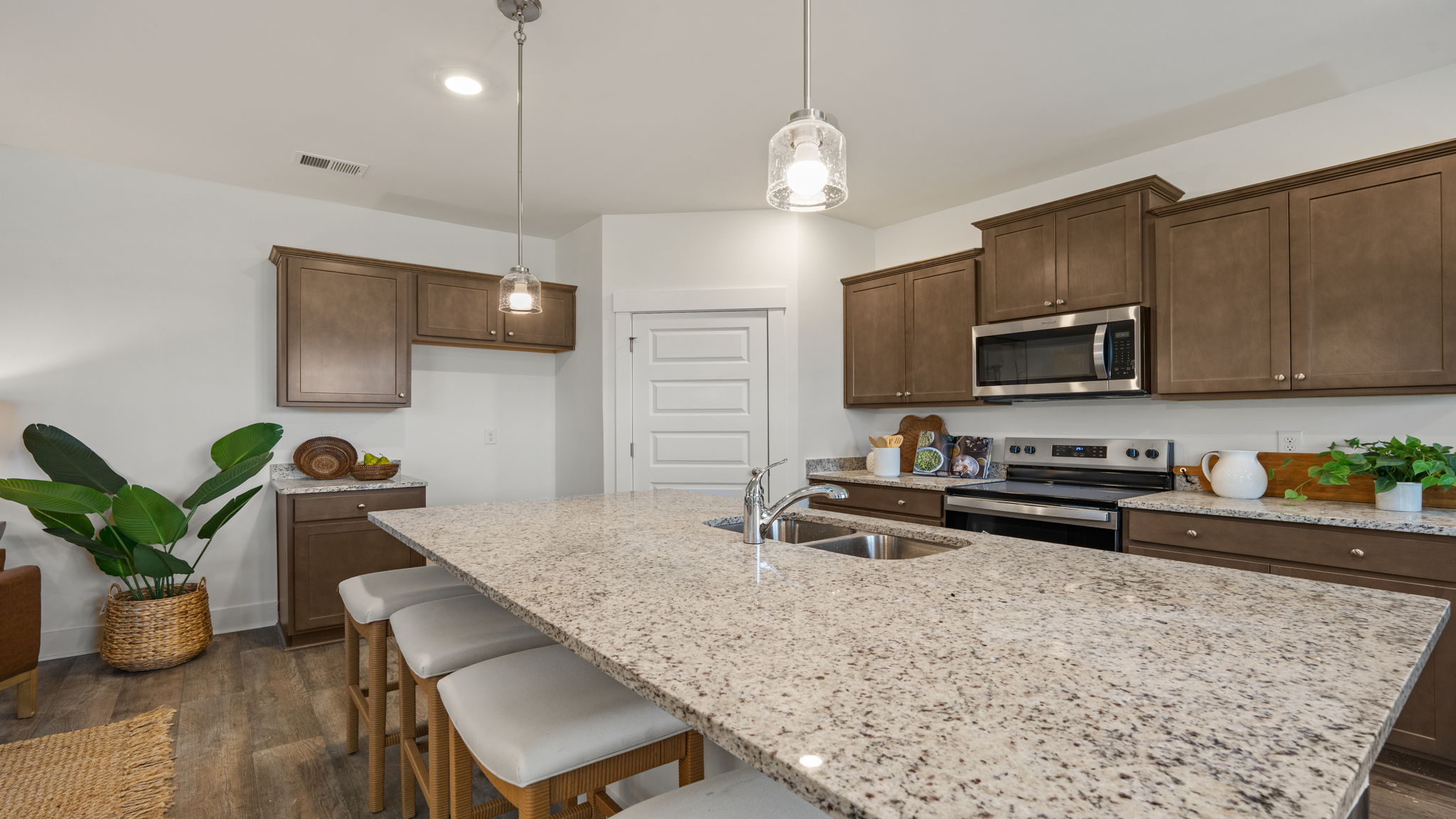 Modern kitchen featuring brown cabinetry, stone-look countertops, stainless steel appliances, and center island.